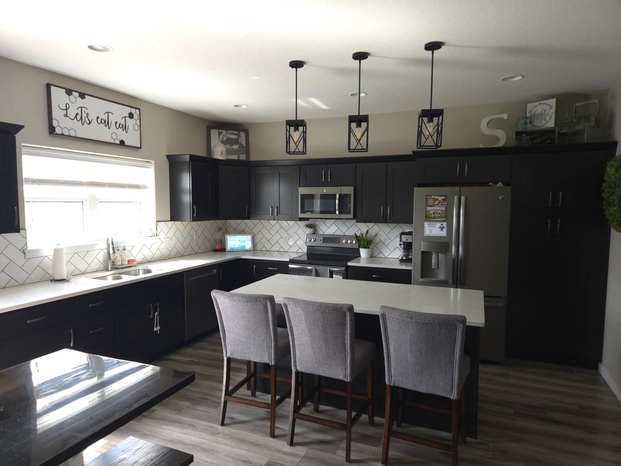 Kitchen at 934 2nd Street Jesup Iowa - dark cabinets, herringbone backsplash, quartz island with seating
